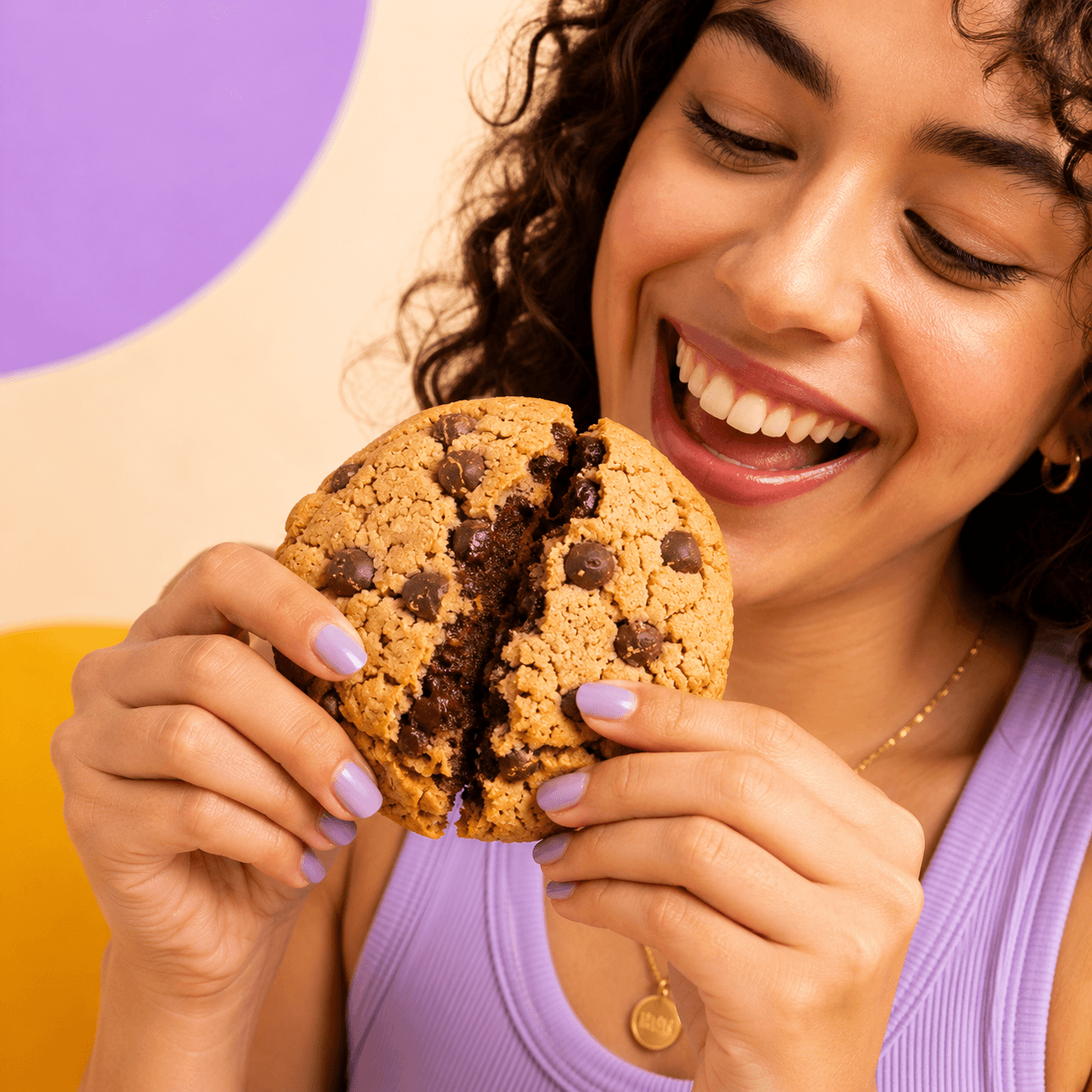Woman smiling while holding a chunky Fatso chocolate cookie